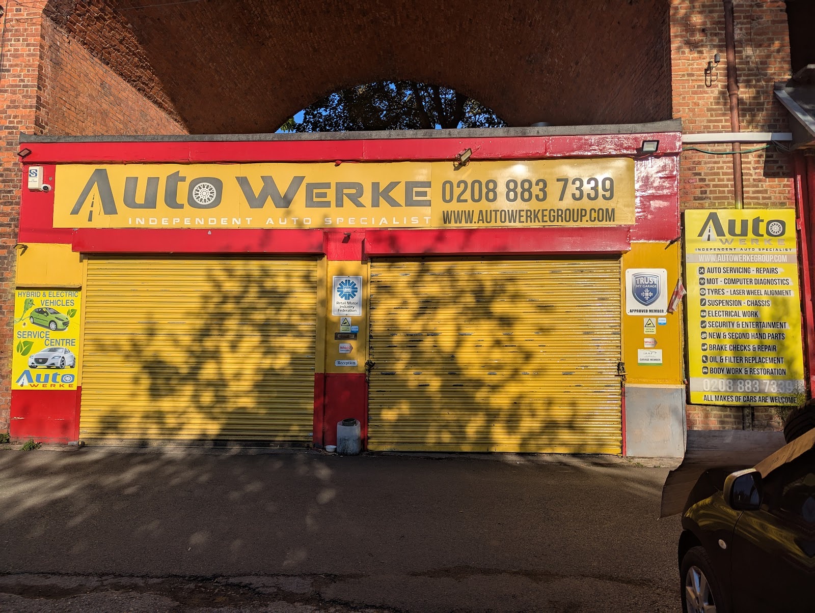 A white Rolls-Royce raised on the ramp inside Auto Werke Group on Unit 7, under the workshop sign